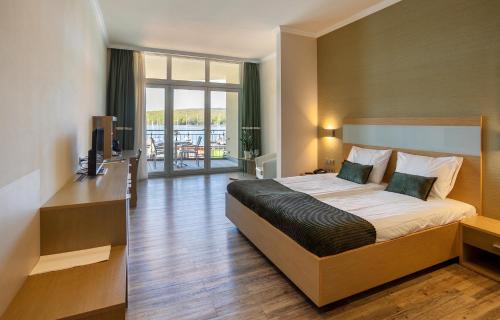a bedroom with a large bed and a balcony at Dormio Hotel Der Seehof in Heimbach