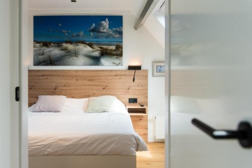 a bedroom with a bed and a painting on the wall at Friese Antillen in Hollum