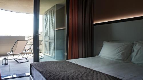 una camera da letto con un letto e un balcone con una sedia di Residence Ormeggio a Grado