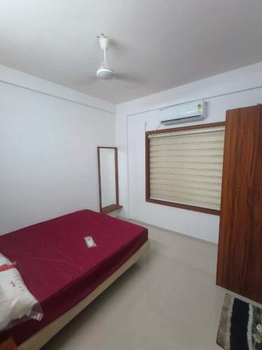 a bedroom with a red bed and a window at Kalpaka lee divine in Guruvāyūr