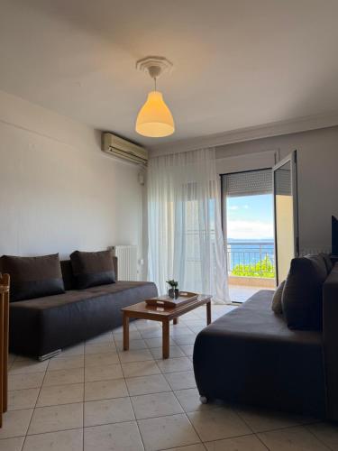 a living room with a couch and a table and a window at EverBlue Suites - Halkidiki Beachfront in Psakoudia