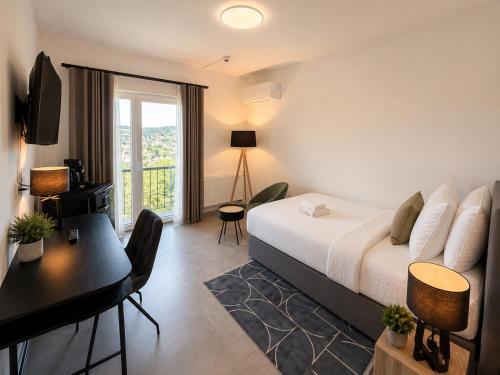 a hotel room with a bed and a desk and a balcony at Elion Hotel Siegen in Siegen