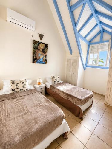 two beds in a room with blue ceilings at VILLA CARAIBE in Sainte-Luce