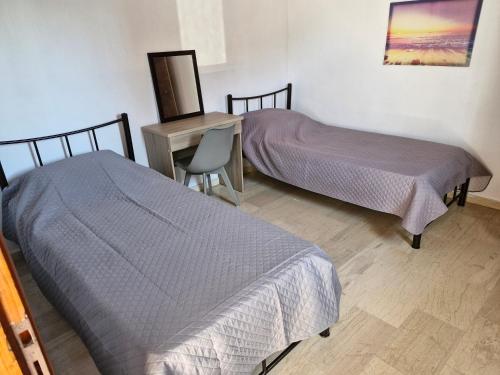two beds in a room with a desk and a chair at Sidari Studios in Sidari