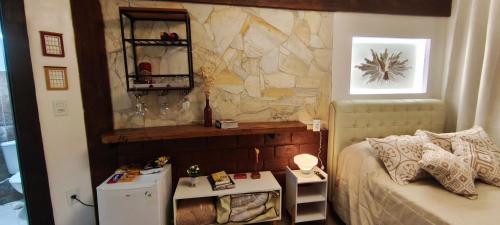 a bedroom with a bed and a stone wall at Espaço Vintage Hospedaria Suíte Alento in Prados
