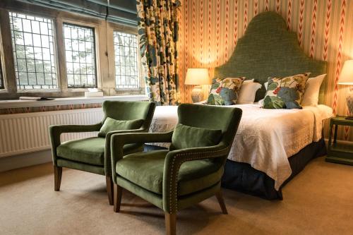 a bedroom with a large bed with two green chairs at Fischers Baslow Hall - Chatsworth in Baslow