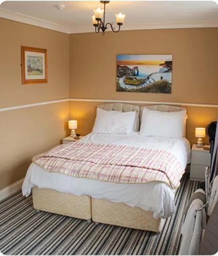 a bedroom with a large bed and two lamps at Trillberry Guesthouse in Weymouth