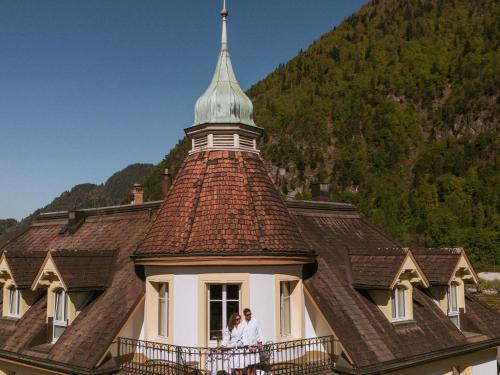 two people standing on a balcony of a building at Royal St. Georges Hotel Interlaken - MGallery Collection in Interlaken