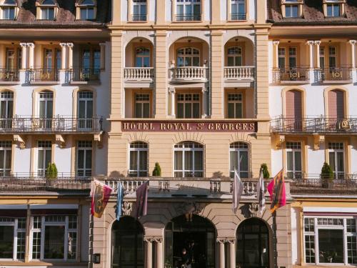 a large building with flags in front of it at Royal St. Georges Hotel Interlaken - MGallery Collection in Interlaken