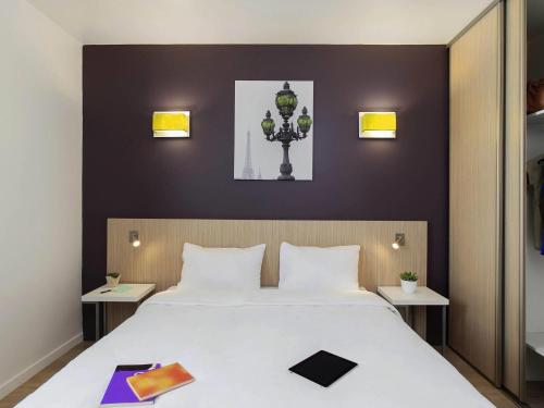 a bedroom with a large white bed with two tables at Aparthotel Adagio Access Paris Clichy in Clichy
