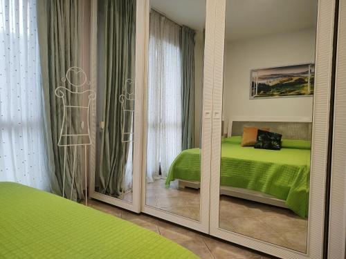 a bedroom with a green bed and a mirror at Cherry House: Giardino Privato & Relax vicino Pisa in Ponsacco