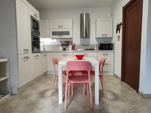 a kitchen with a white table and pink chairs at Cherry House: Giardino Privato & Relax vicino Pisa in Ponsacco