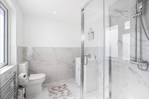 a white bathroom with a toilet and a shower at Large 6-Bed House - 5 Bathrooms w Free Parking by StaySejour in Sompting