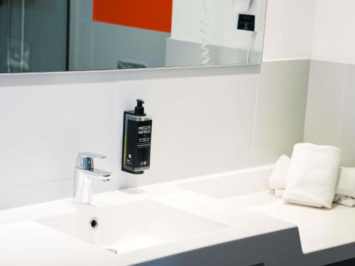 a bathroom with a white sink and a mirror at ibis Styles Caen centre gare in Caen