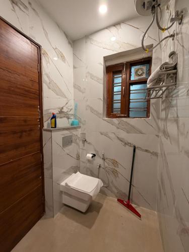 a bathroom with a toilet and a window at Urban Nest By Jassi in Kharar