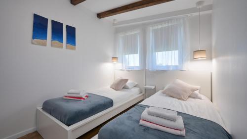 two beds in a room with white walls and windows at Villa Una by Villas Guide in Gornji Kneginec