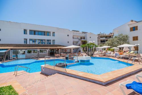 a pool with chairs and umbrellas next to a building at Aparthotel Flora in Port de Pollensa