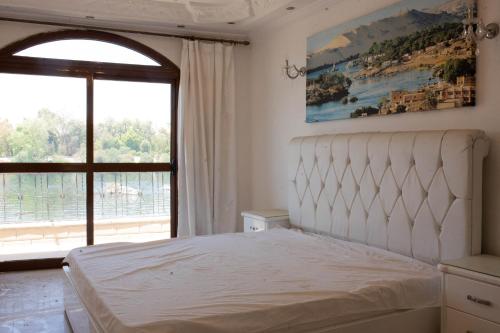 a bedroom with a bed and a large window at Island House in Jazīrat Aswān