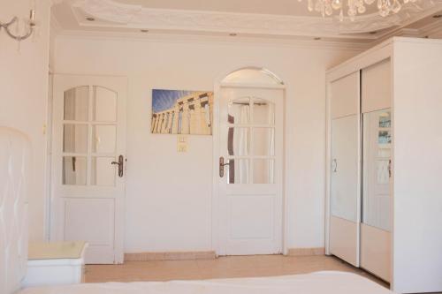 a white room with white doors and a chandelier at Island House in Jazīrat Aswān