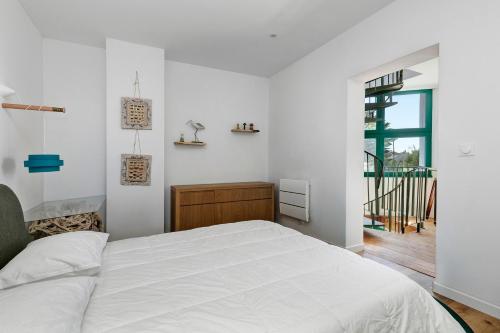 a white bedroom with a bed and a window at Les terrasses de Joce in Batz-sur-Mer