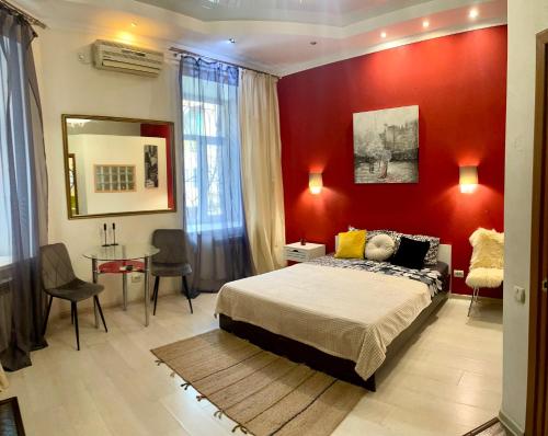 a bedroom with a red wall with a bed and a table at Apartments De-Ribas in Odesa