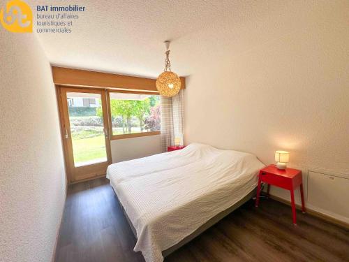 a bedroom with a bed with a red table and a window at Scierie A Meya 118 - Appartement charmant proche des télécabines et du village in Vercorin
