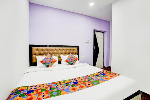 a bedroom with a large bed with colorful pillows at FabHotel Triotel Inn in Dhanbād