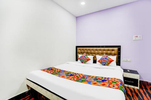 a bedroom with a large white bed with colorful pillows at FabHotel Triotel Inn in Dhanbād