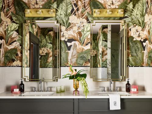 a bathroom with two sinks and a wallpaper with plants at Zelda Dearest in Asheville