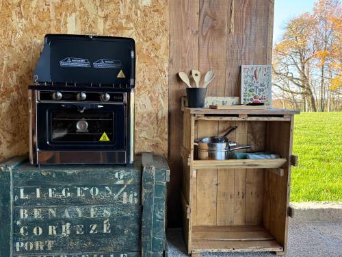 a stove and a wooden cabinet next to a table at Sunrise Tent in Sageau