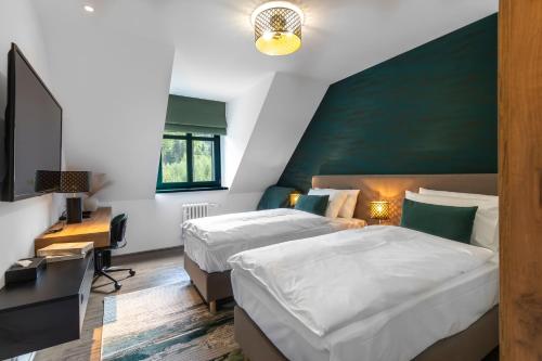 a bedroom with two beds and a desk and a television at Hotel Ráztoka in Trojanovice