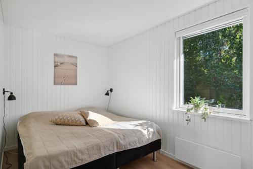 a white bedroom with a bed and a window at Newly Renovated And Modern Cottage Near The Beach in Hornbæk