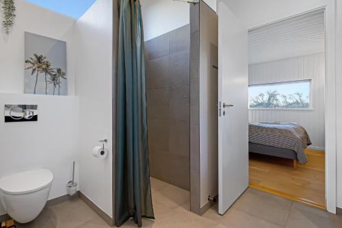 a bathroom with a shower with a toilet and a bed at New Modern Holiday Home Near The Beach in Aabenraa