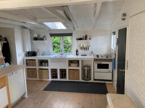 a kitchen with white counters and a sink and a stove at Cozy And Modernized Fishing Cabin in Hornslet