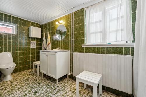 a green tiled bathroom with a sink and a toilet at Cozy Holiday Home In Marstal On Ærø in Marstal