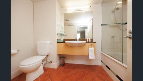 a bathroom with a toilet and a sink and a shower at Esplanade 88 in Darwin