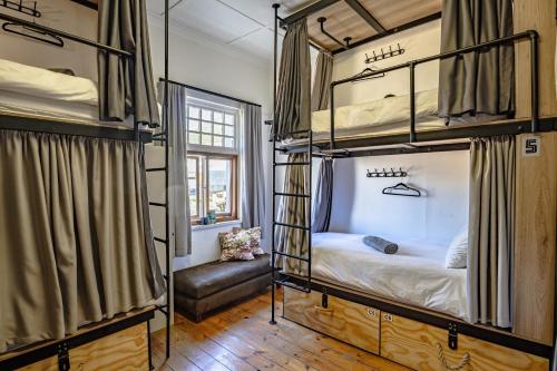 two bunk beds in a room with a couch at Adamastor Backpackers in Muizenberg