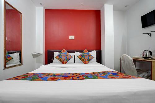 a bedroom with a white bed with a red wall at FabHotel DP International in Patna