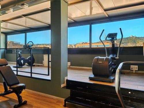 ein Fitnessstudio mit zwei Ellipsentrainern und einem großen Fenster in der Unterkunft Mercure Barcelona Condor in Barcelona