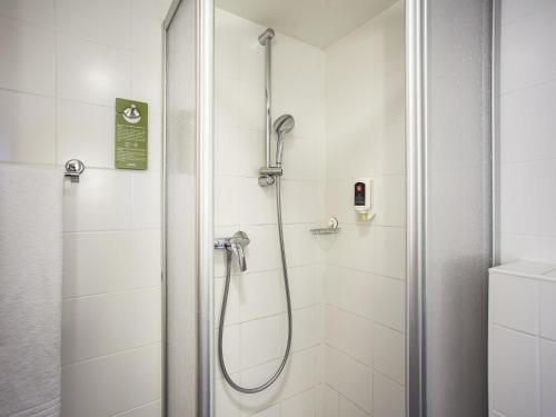 a shower in a bathroom with white tiles at ibis Wörthersee in Pörtschach am Wörthersee