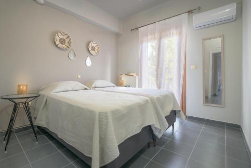 a white bedroom with a bed and a window at StayinPyrgi in Pyrgi