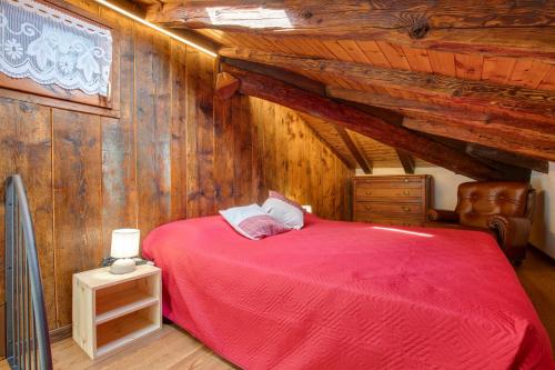 a bedroom with a red bed and wooden walls at Casa Piertor Morgex in Morgex
