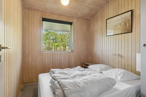 ein Schlafzimmer mit einem Bett in einem Zimmer mit Fenster in der Unterkunft Charmantes Backsteinhaus Mit Sauna Und Fjordblick in Ørsted