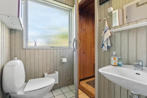 ein Badezimmer mit Toilette, Waschbecken und Fenster in der Unterkunft Charmantes Backsteinhaus Mit Sauna Und Fjordblick in Ørsted