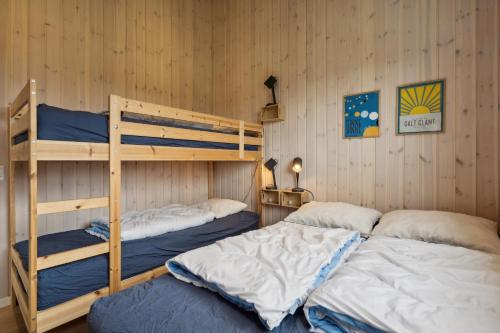 zwei Etagenbetten in einem Zimmer mit zwei Einzelbetten in der Unterkunft Schönes, Neues Haus Am Meer in Aabenraa