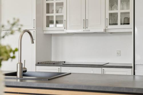 a kitchen with white cabinets and a sink at Cozy Central House Near The Sea in Brenderup