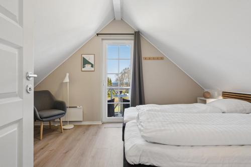 a bedroom with two beds and a chair and a window at Cozy Central House Near The Sea in Brenderup