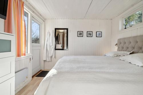 a white bedroom with a large bed and a window at Cozy Cottage Only 500 M From The Sea in Gilleleje