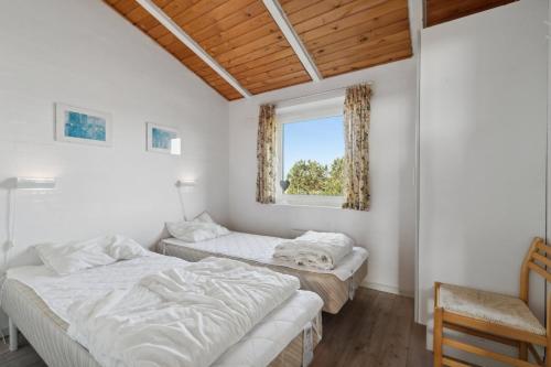 two beds in a room with a window at Pool House Close To The Coast in Vestervig