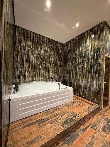 a bath tub in a room with a wooden wall at Bazarstore Montin Hotel in Baku